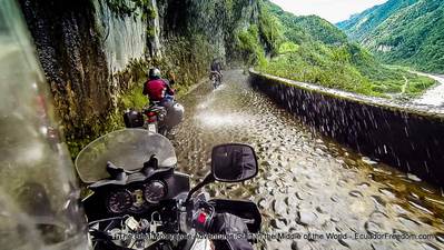 motorcycles riding on cobbled road to banos ecuador under waterfall