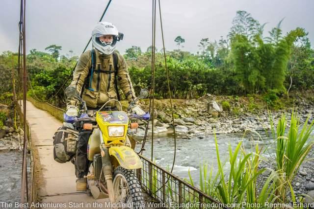 riding suzuki dr650 dual sport motorcycle over a metal bridge in ecuador