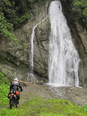 motorcycle riding towards a waterfall on la bonita road in ecuador