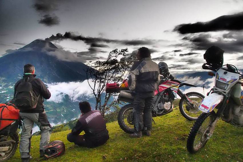 motorcycle tour group looking at erupting volcano in ecuador