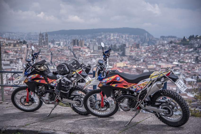 two dual sport dirt bikes motorcycles with a view of quito ecuador down below